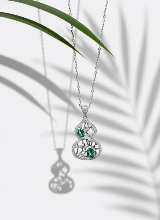 Elysia lab-grown gemstone necklace collection featuring a blue sapphire teardrop pendant, a rose pink round solitaire necklace, and a red emerald-cut gemstone necklace with diamond halo on a white background.